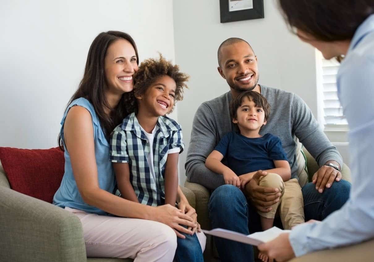 A smiling family with two children speaking with a professional