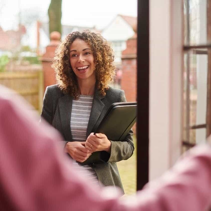 Smiling social worker at a client’s front door