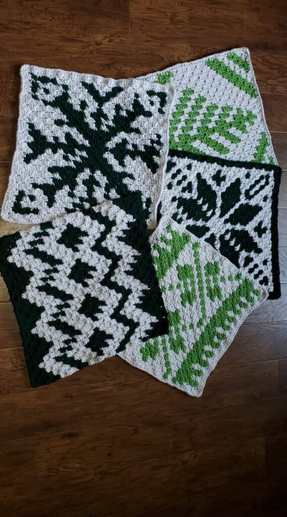 Handcrafted Nordic winter crochet squares in green, black, and white for holiday decor.