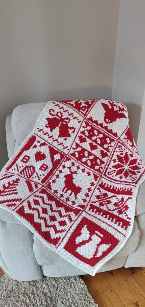Red and white Nordic winter crochet blanket with reindeer and snowflake patterns.