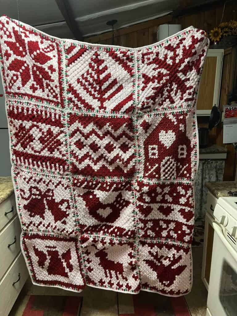 Cozy Nordic winter crochet blanket with red and white snowflake and heart patterns.