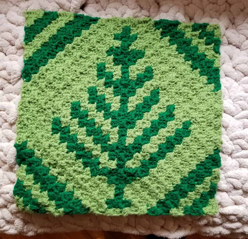Nordic winter crochet blanket with green pine tree pattern.