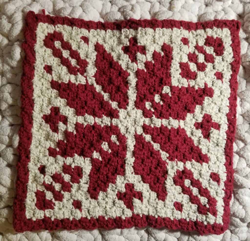 Handcrafted Nordic winter crochet blanket with red and cream yarns.