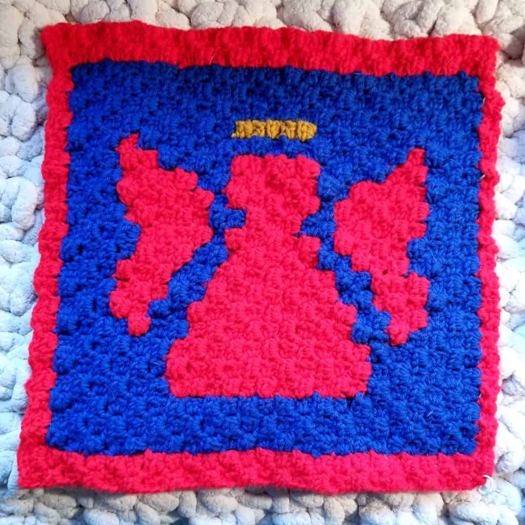 Colorful angel and devil motifs crochet blanket for Christmas decor.