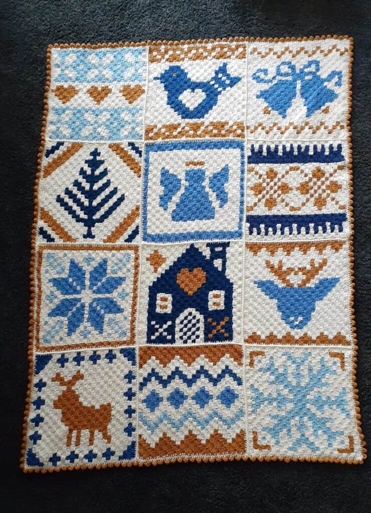 Afghan featuring Nordic winter motifs in blue, white, and brown yarns. Perfect for holiday crochet p.
