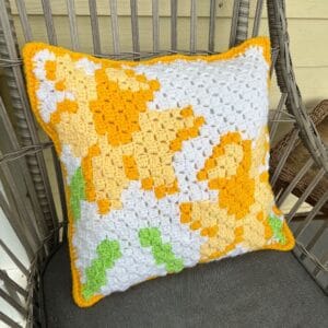 Handcrafted sunflower crochet pillow with vibrant yellow and green accents.