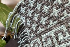 Handwoven wool blanket with intricate patterns and fringed edges.