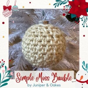 Moss knit Christmas ornament hanging on a white tree branch.
