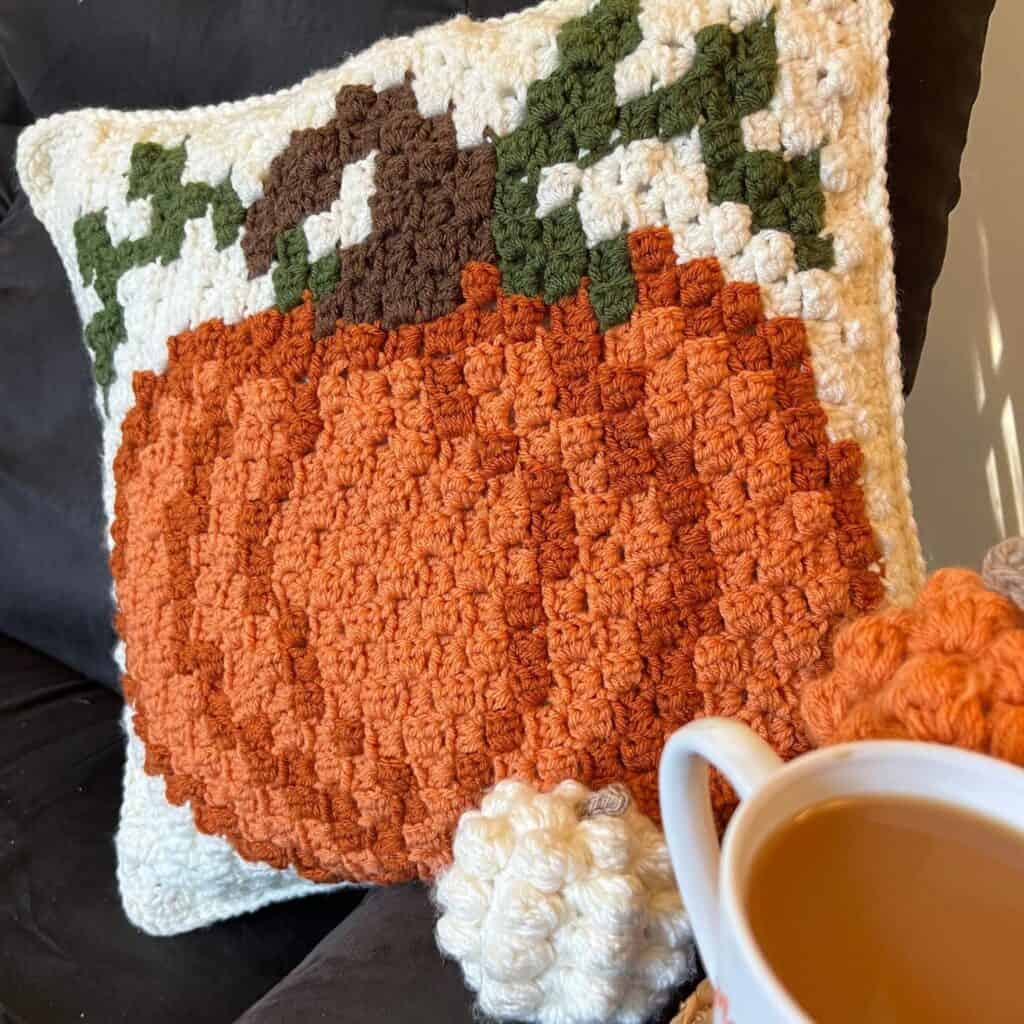 Handmade pumpkin-shaped crochet pillow for autumn decor and cozy home accents.