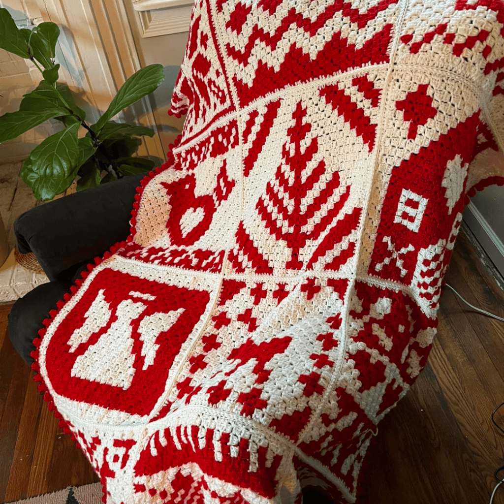 Red and white Nordic-themed crochet blanket with Christmas motifs and geometric designs.