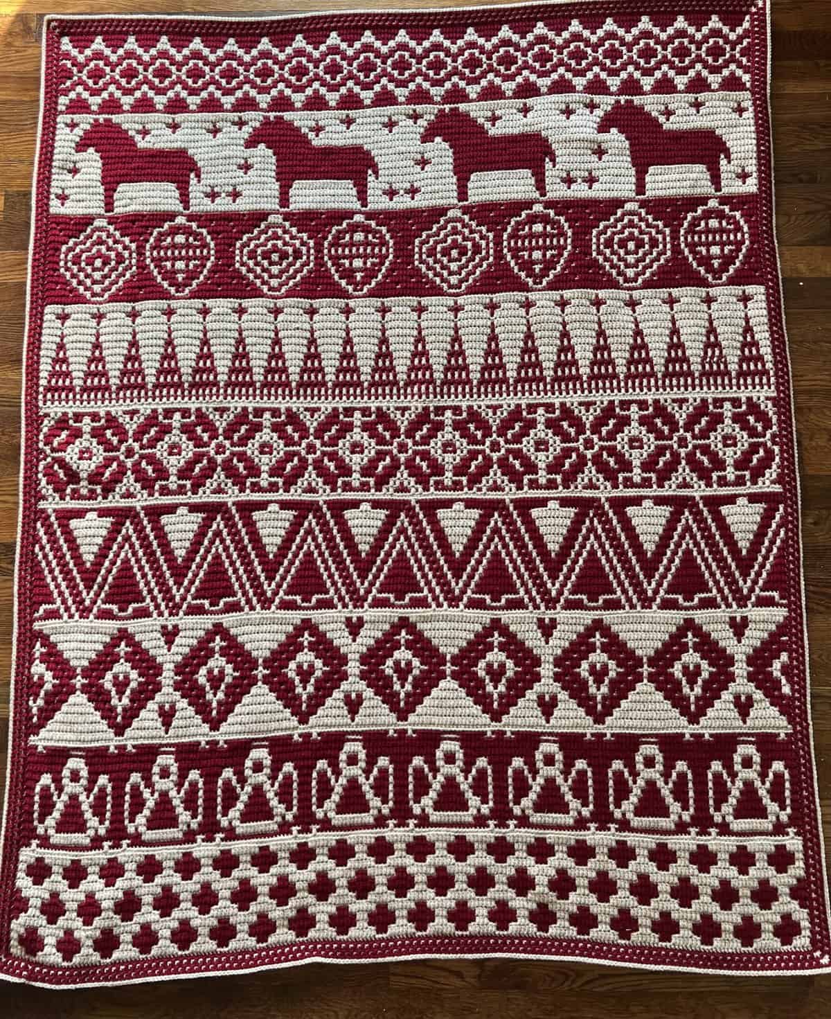 Colorful mosaic crochet Nordic winter blanket featuring reindeer and geometric designs.