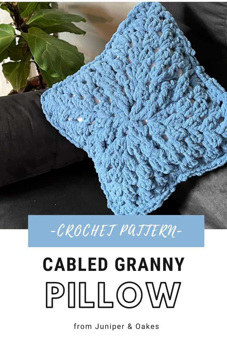 Bright blue cabled granny pillow made with Bernat Blanket Yarn. Perfect for cozy home decor and hand.