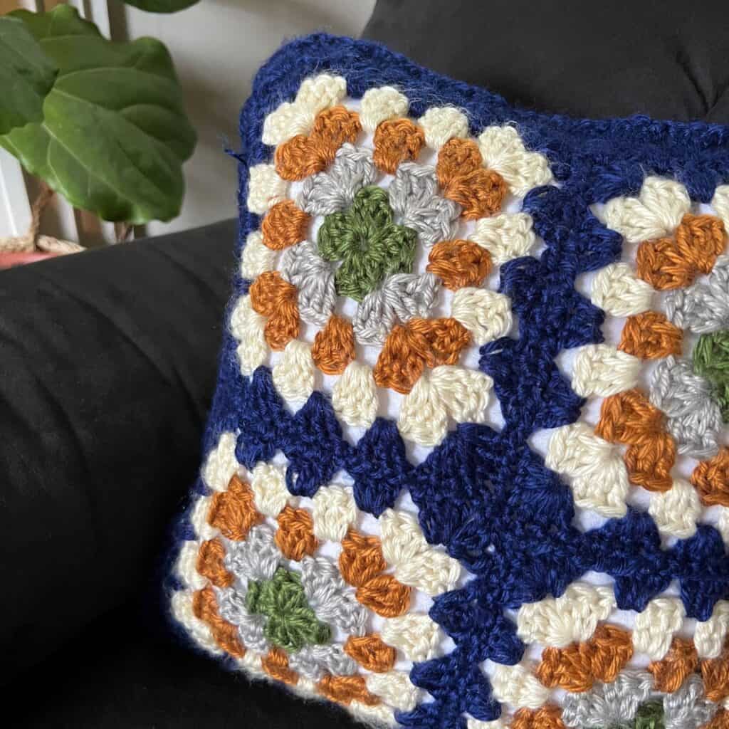 Colorful crochet granny square pillow with vibrant multicolored squares.