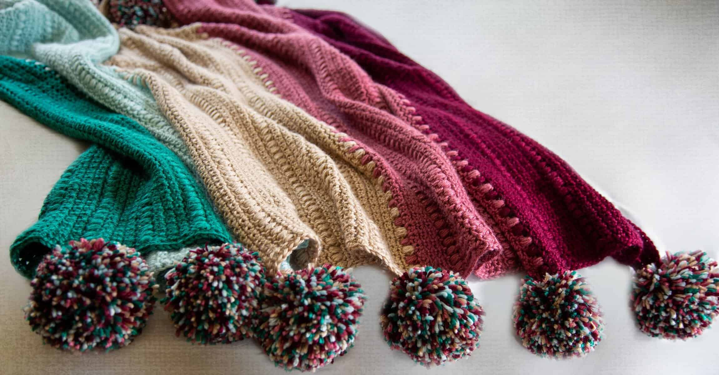 Colorful crochet pom pom blanket perfect for porch and picnic settings.
