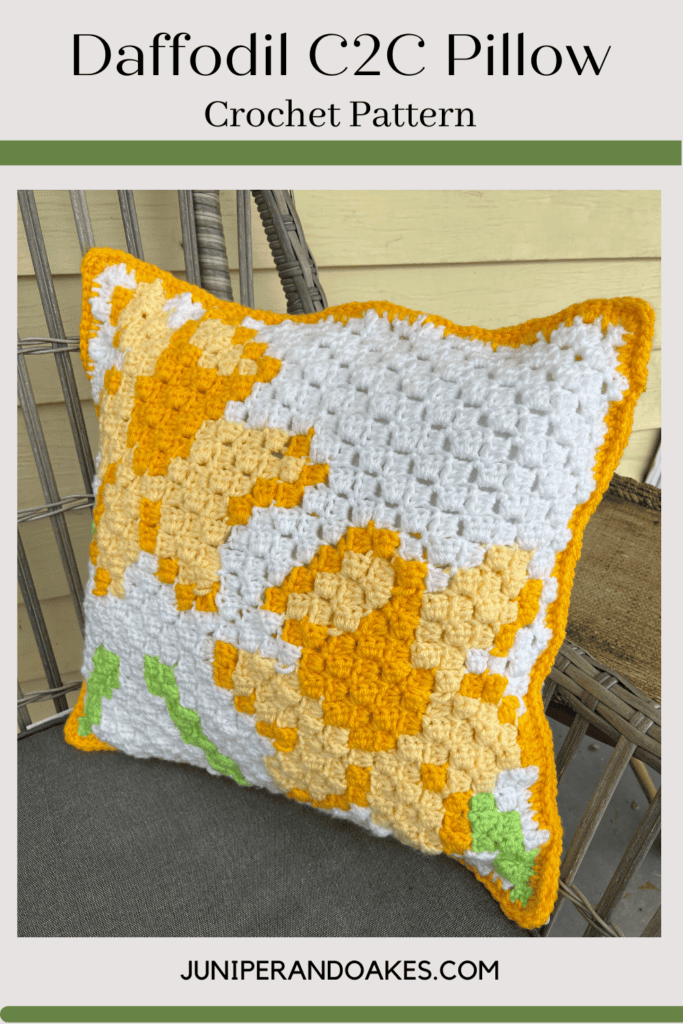 Bright yellow and white daffodil crochet pillow with green accents. Perfect for spring decor or gift.