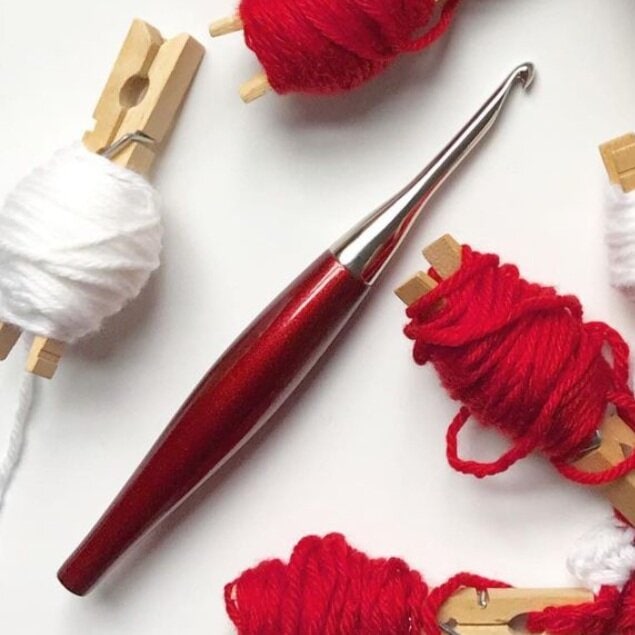 Knitting needles and yarn balls in red and white for crafting.
