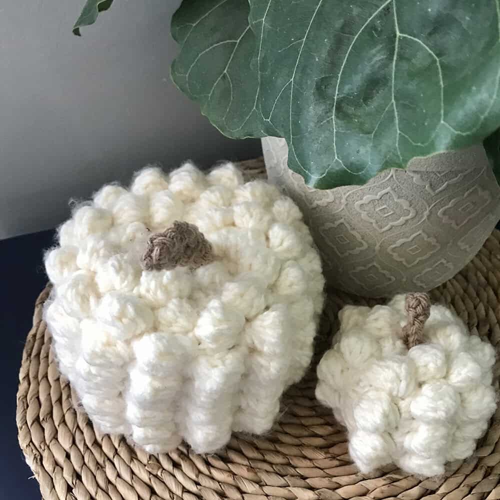 Handmade wool pumpkins with a large green leaf in a decorative setting.