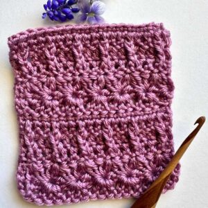 Crochet blossom blanket in pink with textured floral pattern, perfect for cozy home decor or gifting.