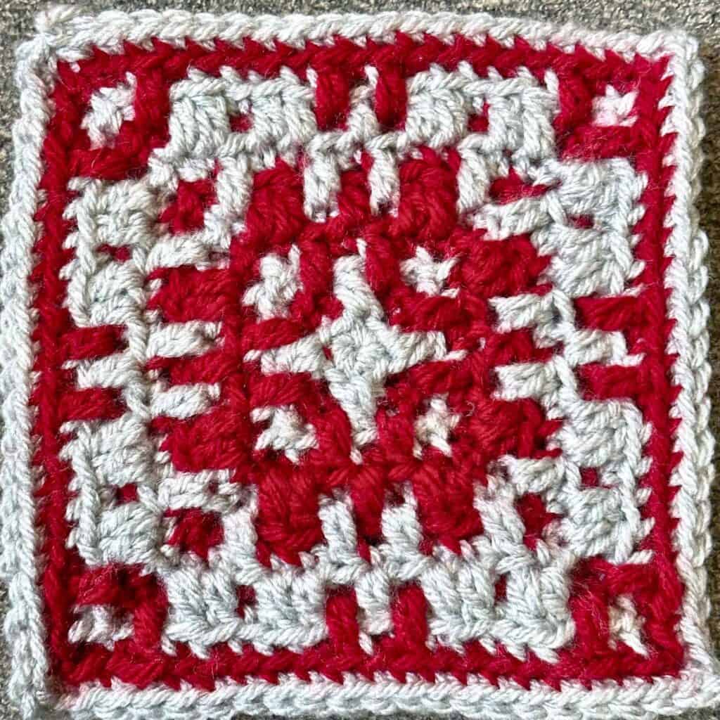 Embroidery textile with red and white geometric design, showcasing detailed craftsmanship.