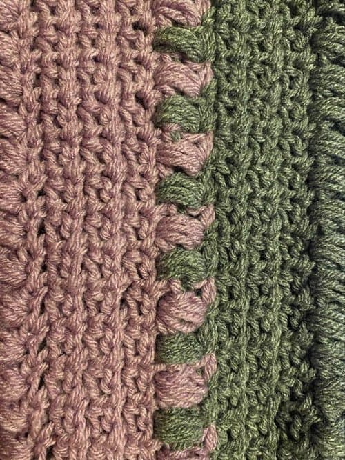 Handwoven textile with pink and green yarns, showcasing detailed craftsmanship and vibrant colors.