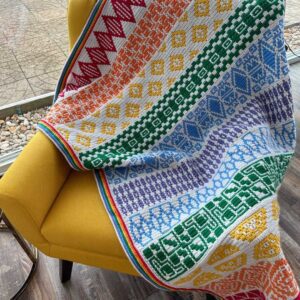 Colorful woven blanket with geometric patterns on yellow chair.
