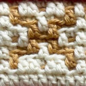 Up of a crochet mosaic pattern in white and tan yarns.