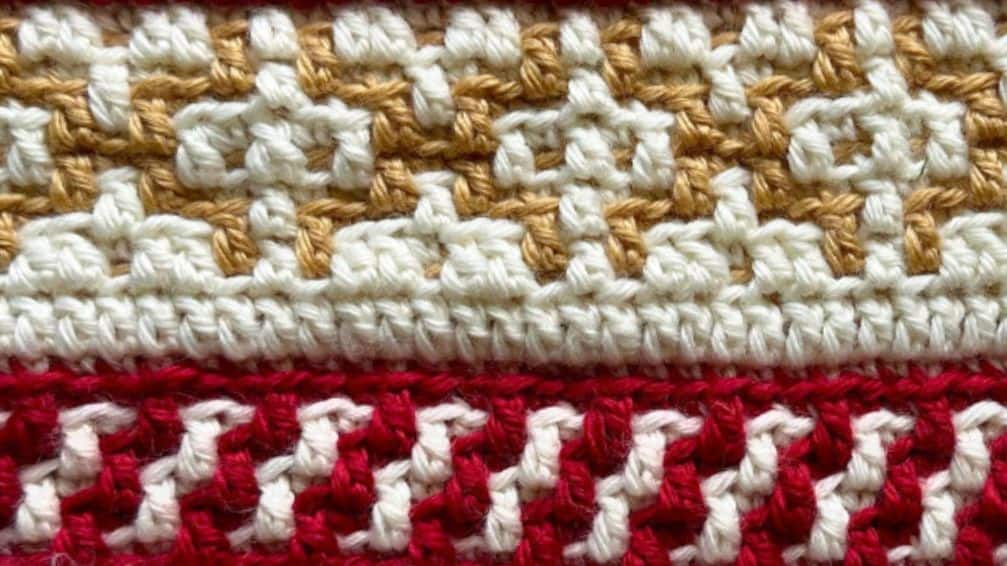 Close-up of crochet gingerbread blanket with white, red, and tan yarns.