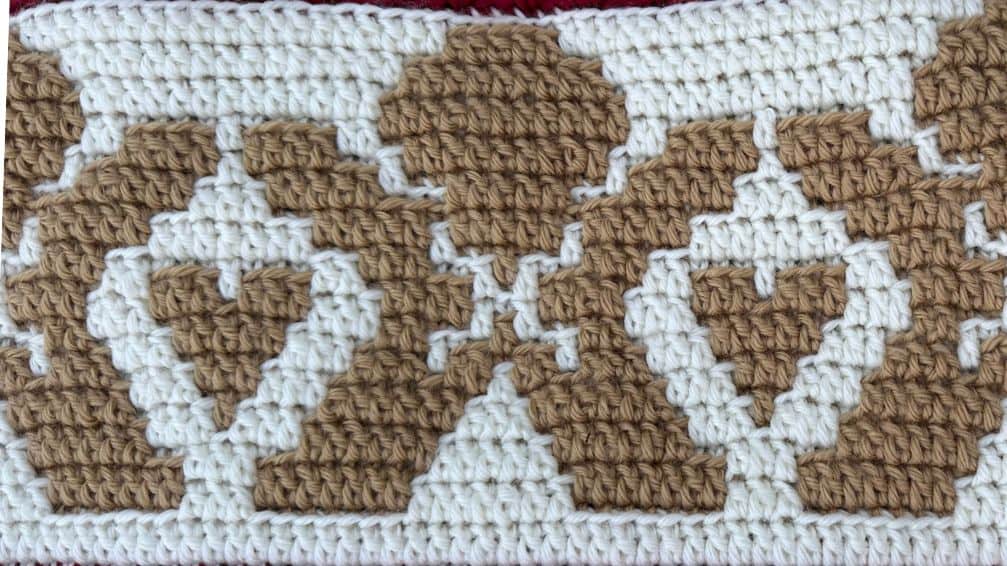 Close-up of a gingerbread-themed mosaic crochet blanket with heart motifs.