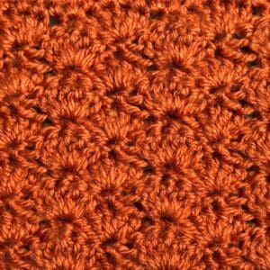 Close-up of orange crochet shell stitch pattern for knitting tutorial.