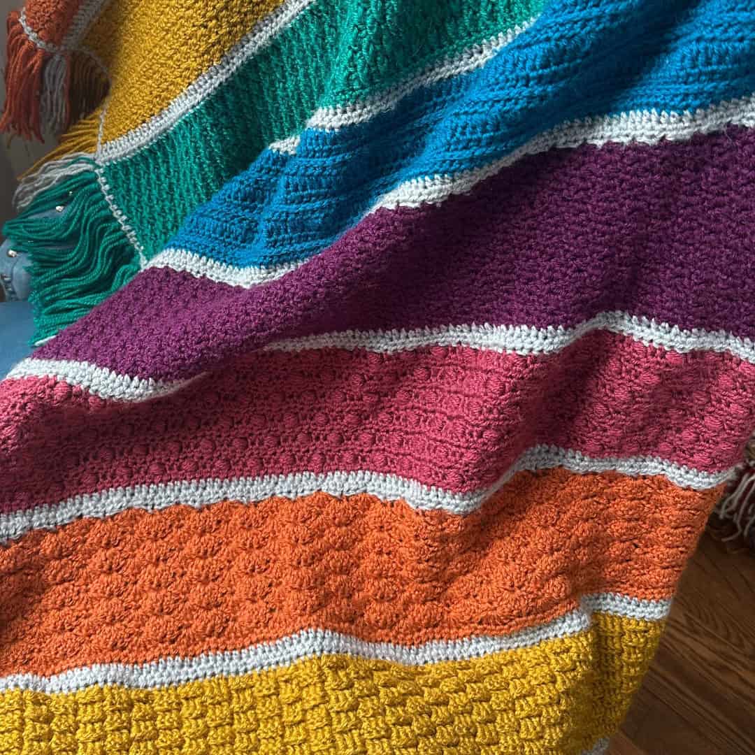 Colored crochet blanket with textured stripes, perfect for a stitch sampler project.