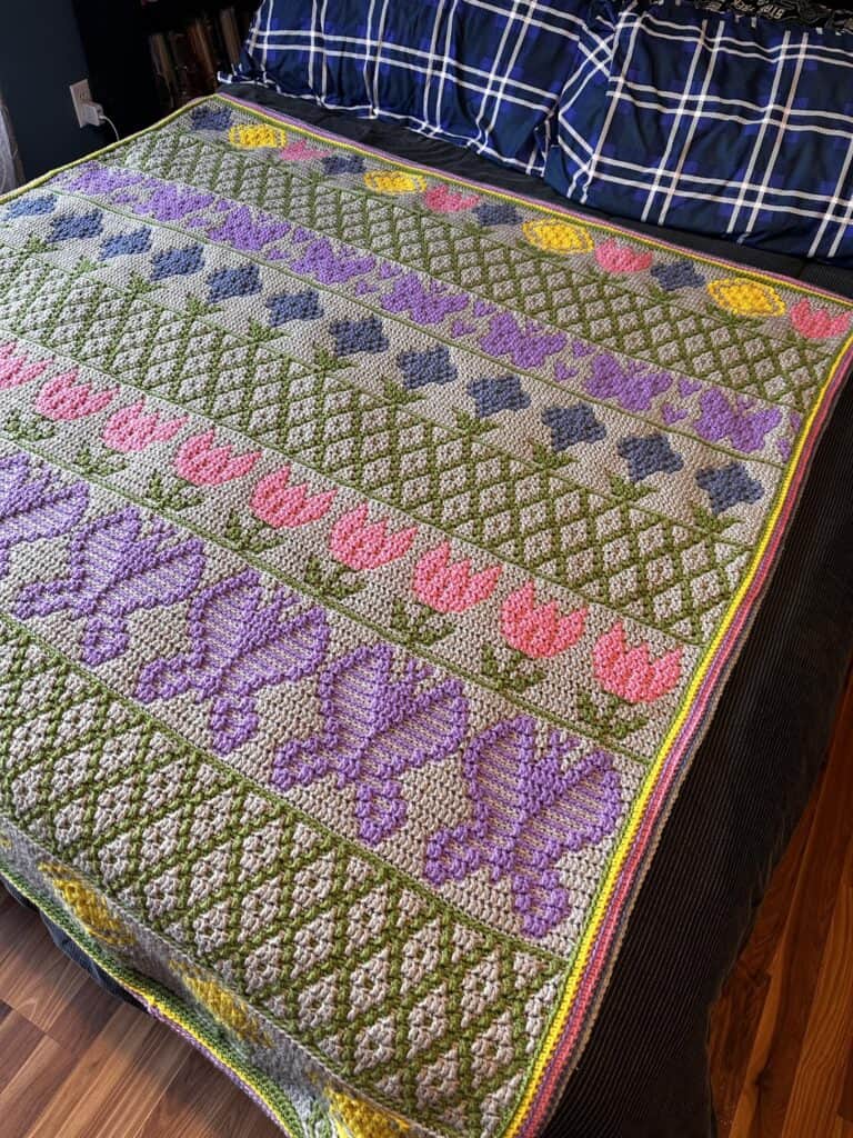 Handmade quilt with floral and geometric patterns, featuring pink, purple, green, and yellow colors.