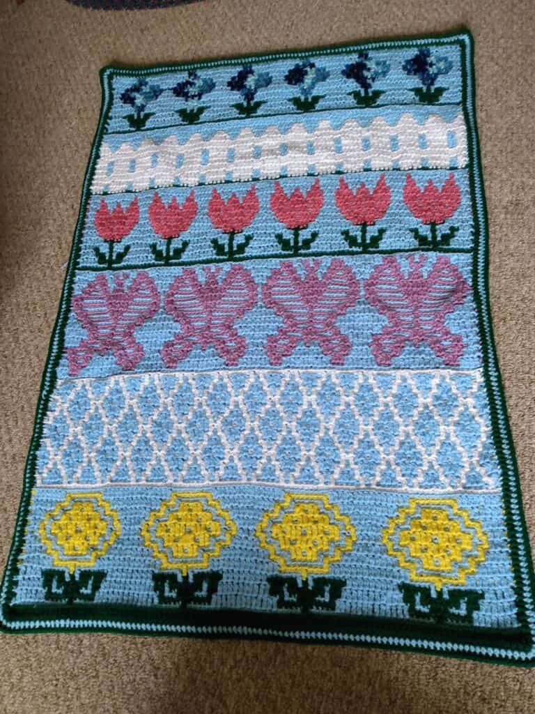 Handcrafted floral needlepoint rug with colorful tulips, hearts, and geometric patterns.