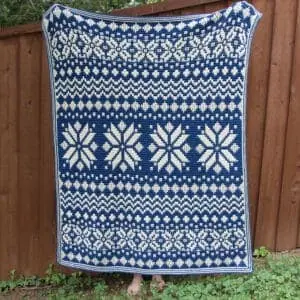Beautiful blue and white Nordic star mosaic crochet blanket displayed outdoors.
