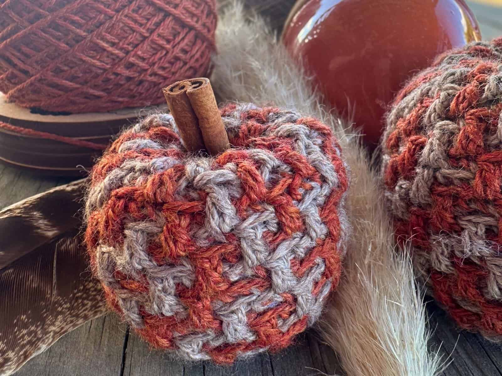 Handmade crochet pumpkin with textured yarn and cinnamon stick accent.
