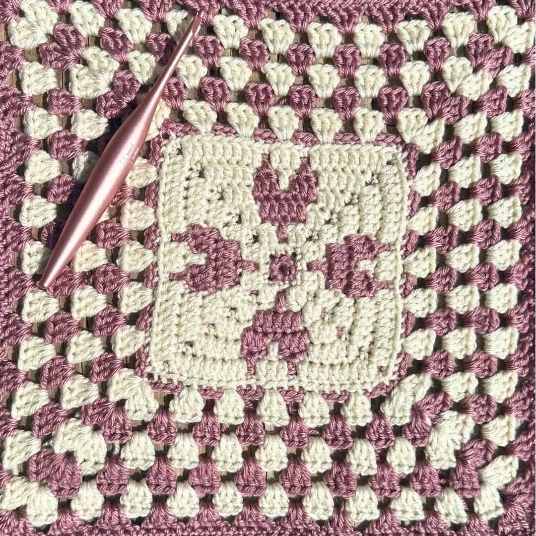 Handmade crochet heart granny square with pink and cream yarns.
