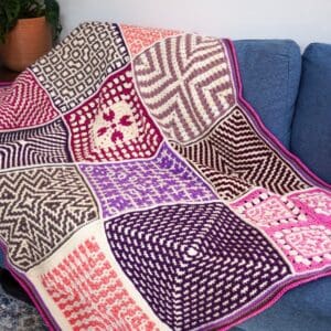 Colorful granny square blanket draped over a blue sofa.