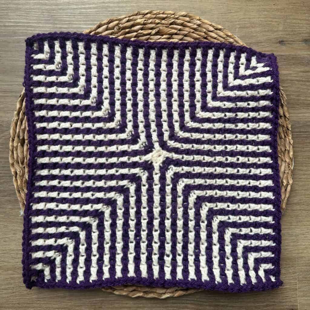 Crossroads Mosaic Crochet Square, arranged on a round raffia mat.