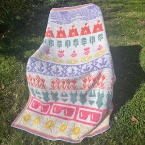 Colorful summer mosaic crochet blanket with various patterns and motifs on a garden chair.