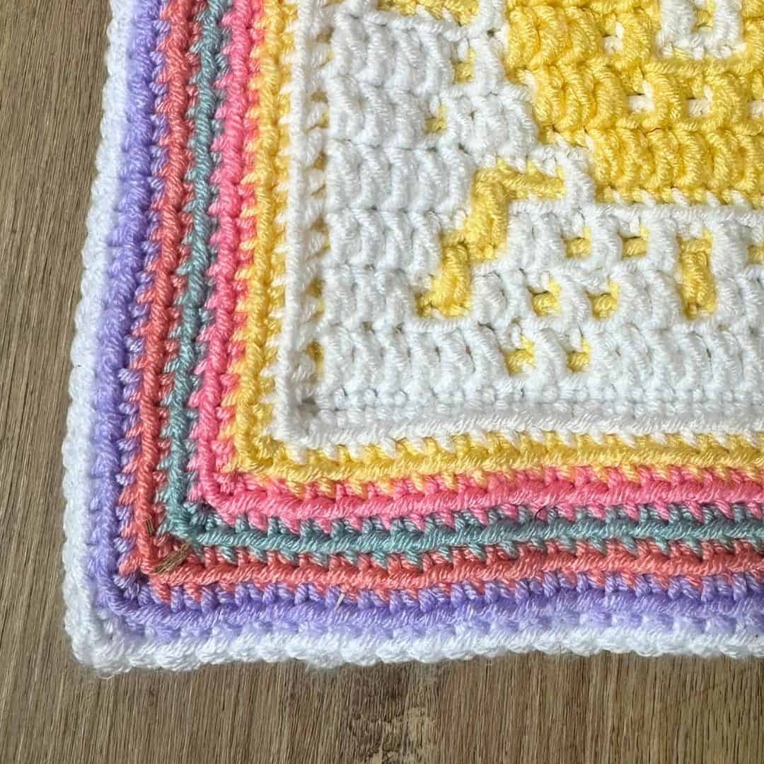 Colorful crochet mosaic blanket with pastel shades and sun design.
