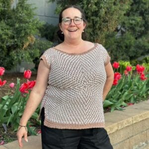 Erin wearing the crochet Mosaic Starburst Tee outdoors with red tulips in the background.