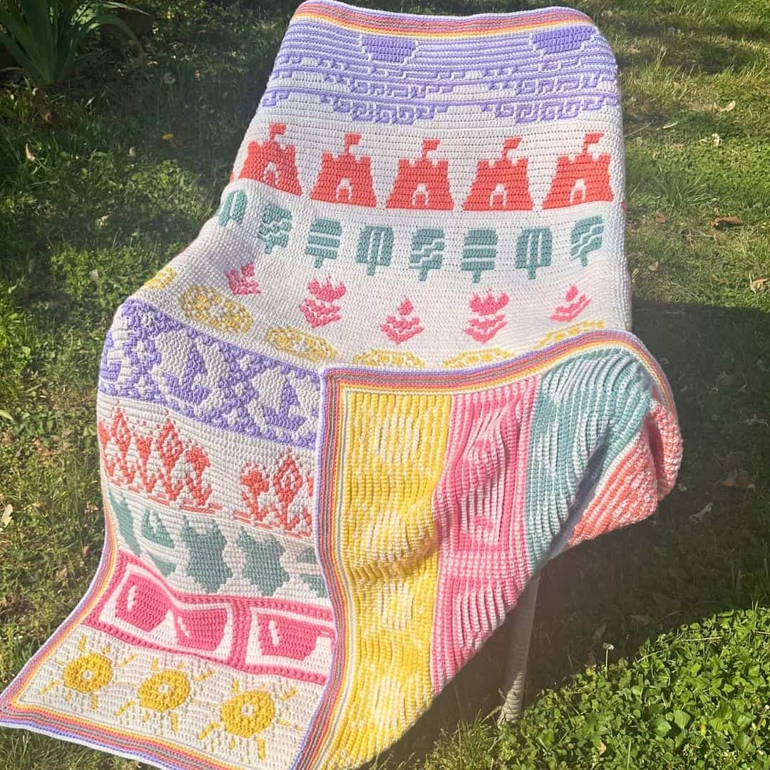 Colorful mosaic blanket with floral and geometric patterns, draped over a chair outdoors.