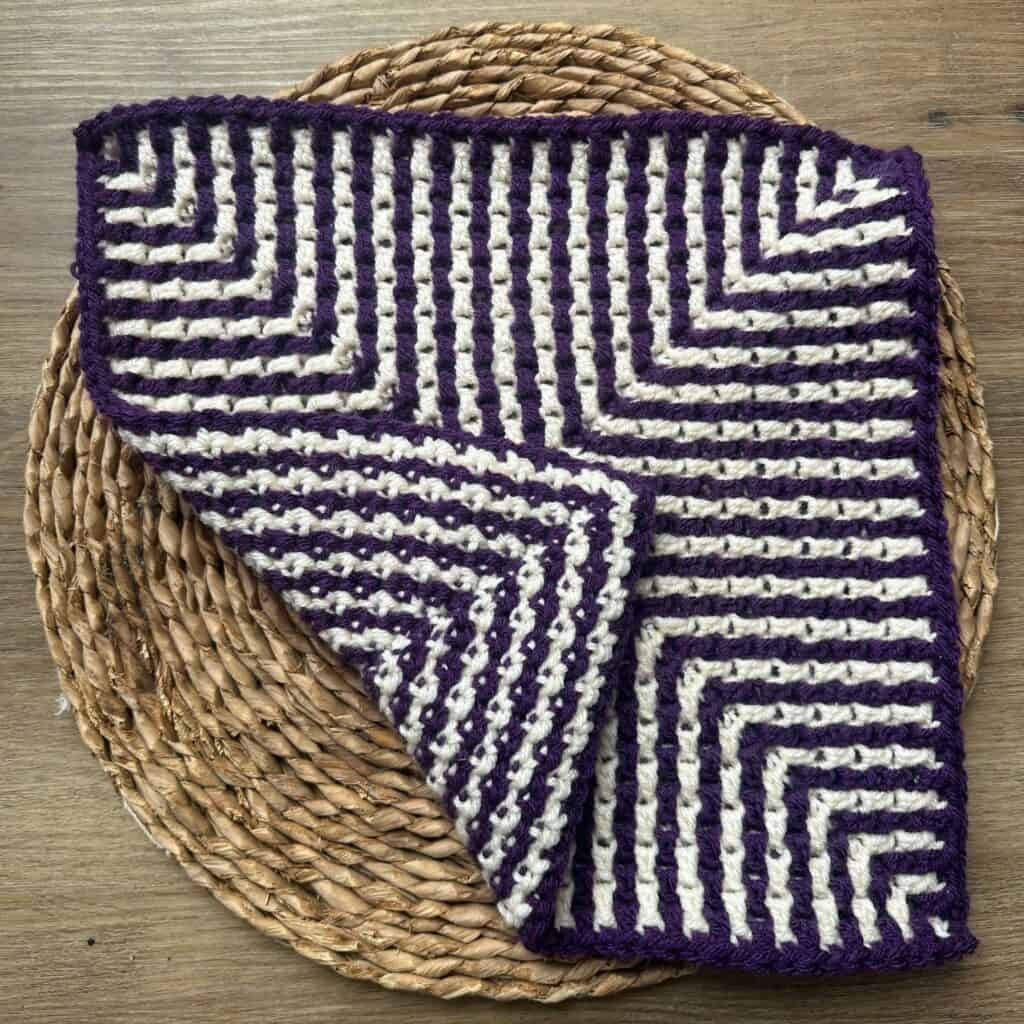 Mosaic crochet square with purple and white geometric design.