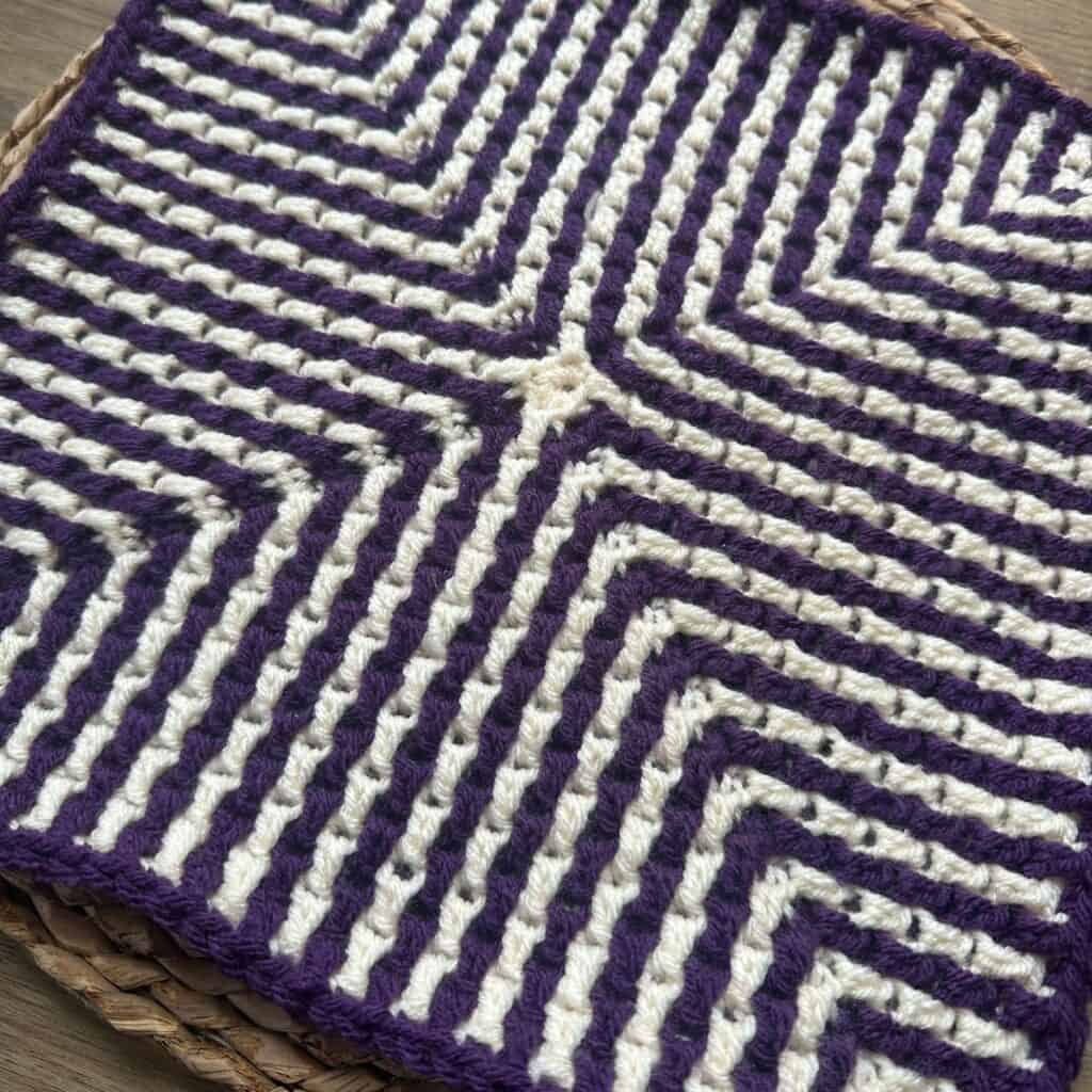 Crochet mosaic square with purple and white geometric pattern, perfect for blankets or decor.