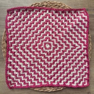 Bright pink and white mosaic crochet square with a geometric ripple pattern. Perfect for home decor.