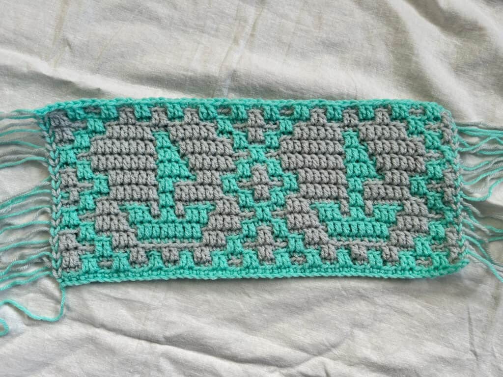 Colorful mosaic crochet sailboats with geometric motifs, in aqua and gray.