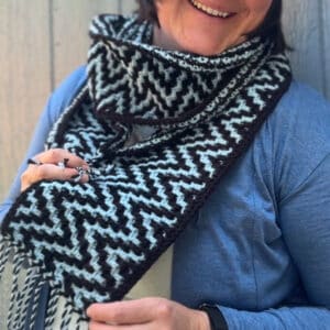 Black and white mosaic zigzag crochet scarf worn by a woman.