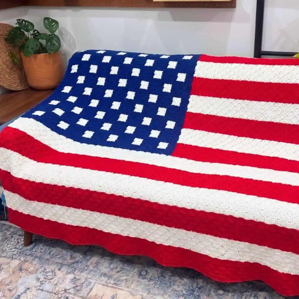 Crochet American flag blanket with red, white, and blue colors on a sofa.