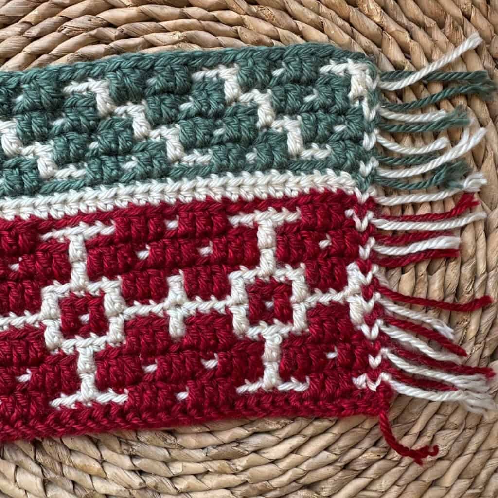 Close-up of a colorful mosaic crochet blanket with red, white, and teal yarns.