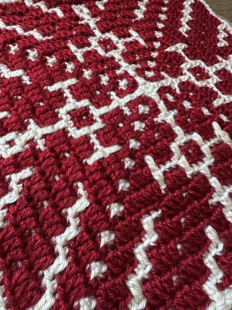 Crochet snowflake square with red and white yarn, intricate pattern for holiday decor.