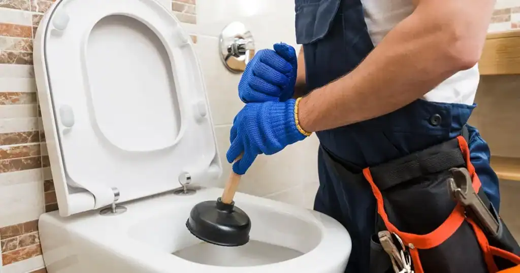 Plumber-Using-Plunger-To-Unclog-Blocked-Toilet-Drain